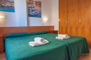 a bedroom with two towels on a green bed at Aptos. Comte D´Empuries in Empuriabrava