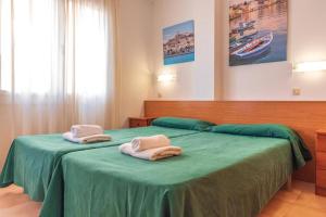 a bedroom with two towels on a green bed at Aptos. Comte D´Empuries in Empuriabrava +79 photos