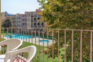 a balcony with two white chairs and a swimming pool at Aptos. Comte D´Empuries in Empuriabrava