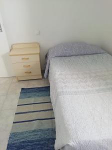 sypialnia z łóżkiem i drewnianą komodą oraz łóżkiem sidx sidx w obiekcie Apartamento Piquinho w mieście Machico