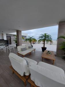 a living room with white furniture and palm trees at Oasis Suite Salinas in Salinas