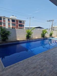 a blue swimming pool with a building in the background at Oasis Suite Salinas in Salinas