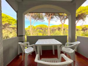 einen Tisch und Stühle auf einer Veranda mit Blick auf die Bäume in der Unterkunft Paguro in Principina a Mare
