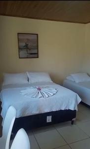 a bedroom with two beds and a picture on the wall at Flat - Condomínio Fechado - Frente Mar in Vera Cruz de Itaparica