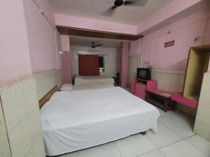a bedroom with a white bed and a tv at JAI MALHAR LODGE in Pune