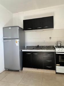 uma cozinha com um frigorífico de aço inoxidável e armários pretos em Nuevo apartamento en primer piso a 7 min del centro em Concordia