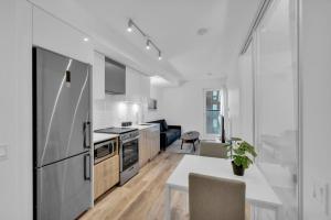 a white kitchen with a table and a refrigerator at Metro Zen on Jarvis - Cozy 2BR - 5 min to City Center in Toronto