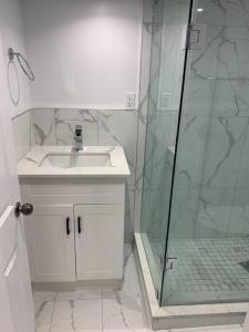 a bathroom with a sink and a glass shower at Adorable 2-Bedroom Basement with Sep Entrance in Ajax