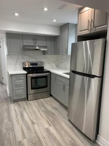 a kitchen with a stainless steel refrigerator and cabinets at Adorable 2-Bedroom Basement with Sep Entrance in Ajax