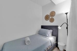 a white bedroom with a bed and a lamp at Metro Zen on Jarvis - Cozy 2BR - 5 min to City Center in Toronto