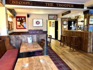 ein Restaurant mit Holztischen und -stühlen und einer Theke in der Unterkunft The Windsor Trooper Pub & Inn in Windsor