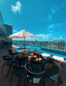 een tafel en stoelen met een parasol naast een zwembad bij Edifício Promenade II Apto 1106-Mandi Hospitalidade in Maceió