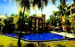 ein Pool vor einem Haus mit Palmen in der Unterkunft Beautiful 1 BHK With Pool Wi-Fi Cooking Gas Gym Caretakers in Velha Goa
