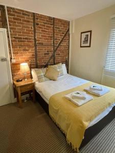 a bedroom with two beds and a brick wall at The Windsor Trooper Pub & Inn in Windsor