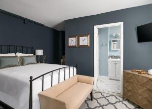 1 dormitorio con paredes azules, 1 cama y 1 silla en Flag House Inn, en Annapolis