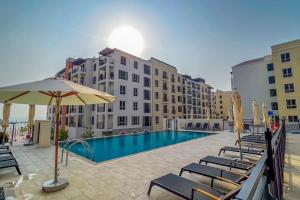 a swimming pool with lounge chairs and an umbrella at Azure Escape !Joyful 1 Bed Apartment close to the Sea! in Dubai