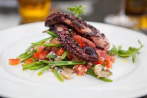 a white plate of food with meat and vegetables at Retro Riverside Wellness Resort in Karlovy Vary