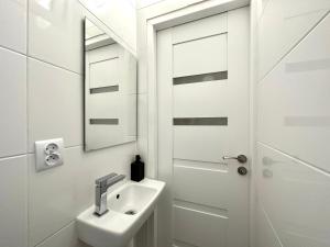 a white bathroom with a sink and a mirror at MMRent Citrus Room in Gdańsk