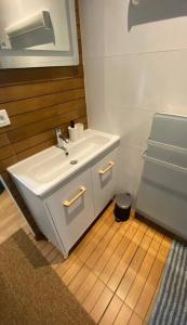a bathroom with a white sink and a wooden floor at Cosy et joli appartement à Saint-Maurice in Saint-Maurice
