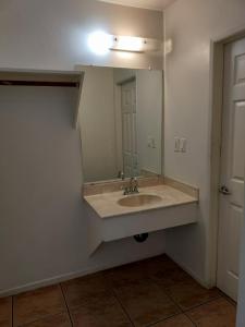 ein Badezimmer mit einem Waschbecken und einem großen Spiegel in der Unterkunft Crown Inn & Suites in Spring Valley