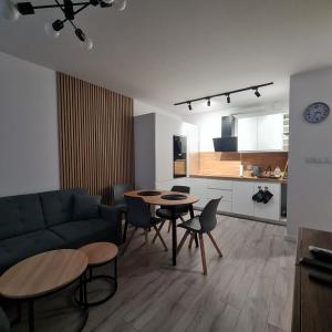 een woonkamer met een bank en een tafel en stoelen bij Green De Lux Apartament Dziwnów in Dziwnów