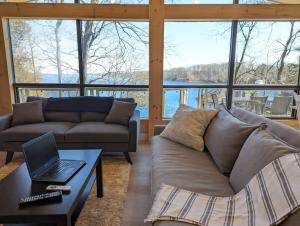 ein Wohnzimmer mit einem Sofa und einem Laptop auf dem Tisch in der Unterkunft Stunning lakefront 4 season cottage in PEC in Bongard