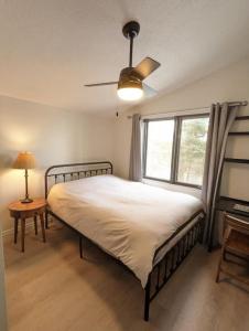 1 dormitorio con 1 cama, ventilador de techo y ventana en Stunning lakefront 4 season cottage in PEC en Bongards
