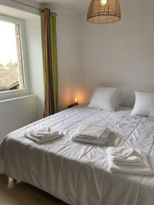 ein weißes Bett mit Handtüchern darauf in einem Schlafzimmer in der Unterkunft Les Séchoirs piscine et spa privatifs in Saint-Romans