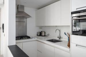 una cocina blanca con armarios blancos y fregadero en Elegant Apartment near Portobello Road Market, en Londres