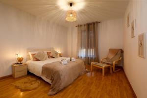 a bedroom with a bed and a chair and a chandelier at ÁGORA in El Burgo de Osma