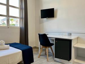a room with a desk and a chair and a bed at Pensión Cassandra in Buzanada