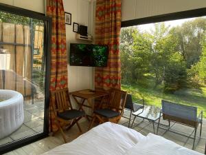 1 dormitorio con 1 cama y ventana con mesa y sillas en JANUS COUNTRY SITE Üdülőházak, en Szakcs