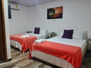 a room with two beds with red and white sheets at Hotel Sunset Beach in Cartagena de Indias