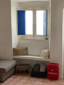 Habitación con ventana con persianas azules y sofá en Casa na aldeia en Albernoa