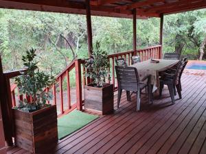 eine Holzterrasse mit einem Tisch und Stühlen darauf in der Unterkunft Hout Huisie in Marloth Park