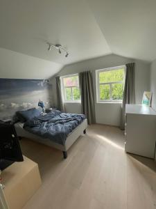 a bedroom with a bed and two windows at Modern cottage in Sogndal