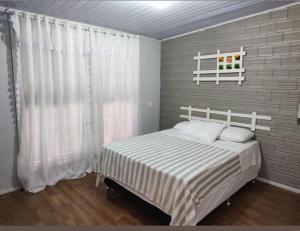 a bedroom with a white bed with white curtains at Portal dos Cânions Pousada in Cambará