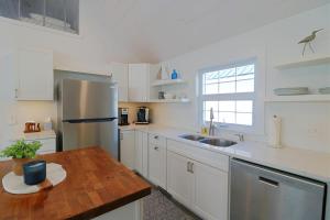 a kitchen with white cabinets and a stainless steel refrigerator at Sandpiper Cottage home in Ashville