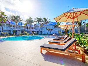 a pool with two lounge chairs and an umbrella at Appartement Saint-Martin , 3 pièces, 4 personnes - FR-1-734-41 in Saint Martin