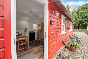 a red house with a door leading to a kitchen at The Red Shed Entire home for 2 Private garden and parking 2 miles from Bury St Edmunds in Whepstead