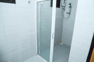 a shower with a glass door in a bathroom at SATK INN Jaffna, Kokkuvil 