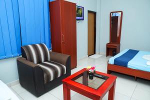 にあるSATK INN Jaffna, Kokkuvilの椅子、テーブル、ベッドが備わる客室です。