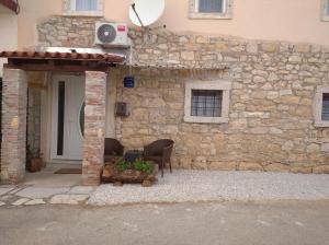 a stone building with two chairs and a door at Apartman Lari in Vižinada