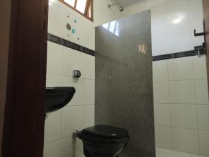 uma casa de banho com um WC preto e um lavatório. em TEMPLÁRIOS ECOVILLA Pousada em Pirenópolis