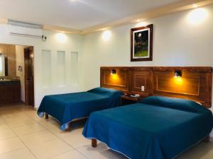 two beds in a hotel room with blue sheets at Hotel Santa Engracia in Ciudad Valles