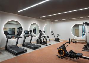 - une salle de sport avec plusieurs tapis de course, elliptiques et miroirs dans l'établissement Hotel Verdant, à Racine
