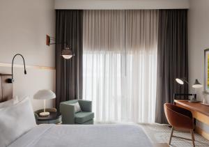 una camera d'albergo con un letto, una sedia e una finestra di Hotel Verdant a Racine