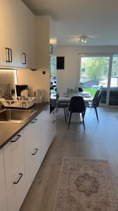 une cuisine avec des placards blancs et une salle à manger avec une table dans l'établissement Årossanden feriesenter, Søgne, Kristiansand, à Kristiansand