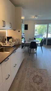 a kitchen with white cabinets and a dining room with a table at Årossanden feriesenter, Søgne, Kristiansand in Kristiansand