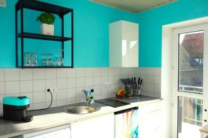 uma cozinha com um lavatório e uma parede azul em HAPPY HOMES - Up to 5 - Küche - W-LAN - Netflix - Honig - Balkon em Nidda